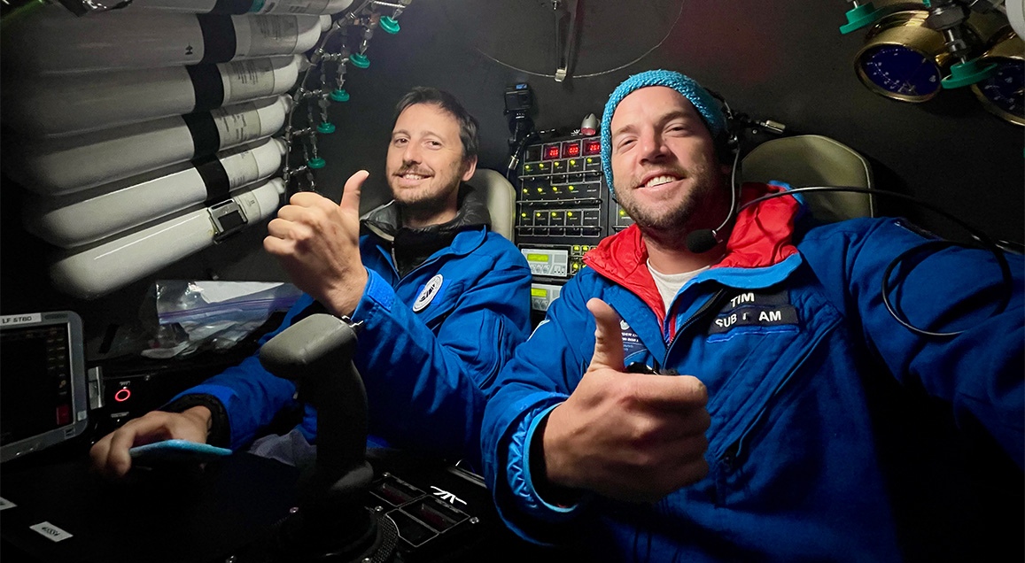 Portrait de Jérémie Morizet et Tim Macdonald dans un sous-marin, souriant et levant leurs pouces